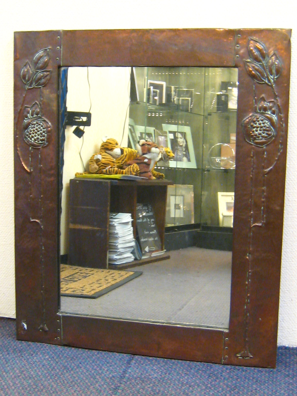 A copper framed Art Nouveau mirror embossed with stylised leaf and pomegranate forms after Charles