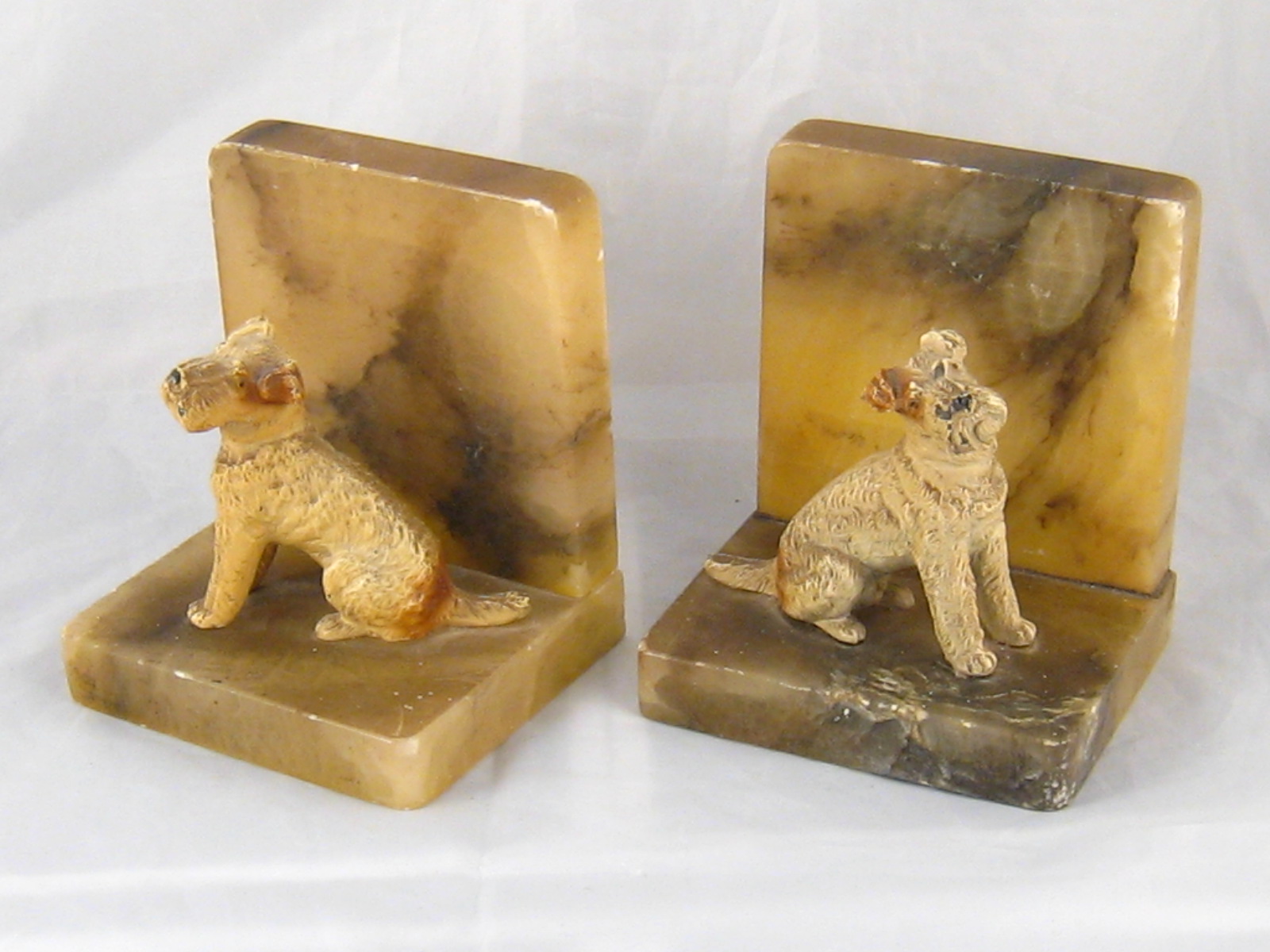 A pair of onyx bookends with seated 7.5cm. high cold painted cast dogs.