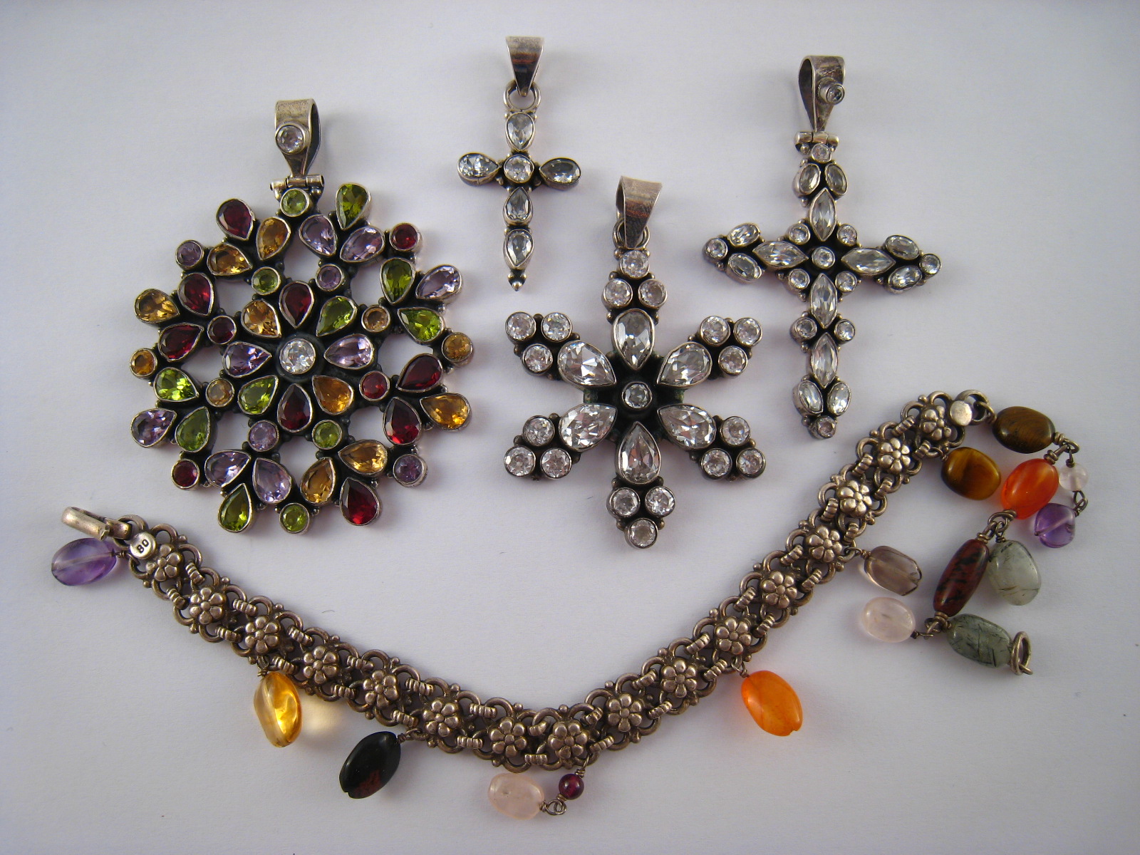 A mixed lot comprising four white metal (tests silver) pendants set with various stones,