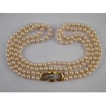 A two row cultured pearl necklace with a yellow metal (tests 18 carat gold) diamond set clasp,