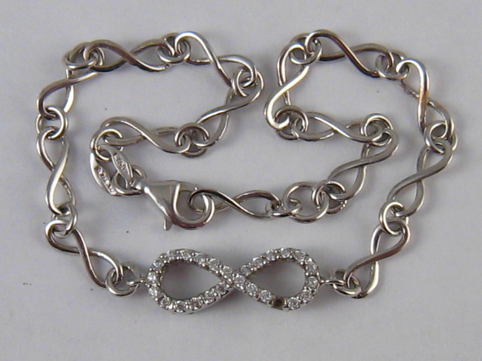A white metal (tests 18 carat gold) CZ set bracelet, approx. 16cm long, 4.2gms. One stone missing.