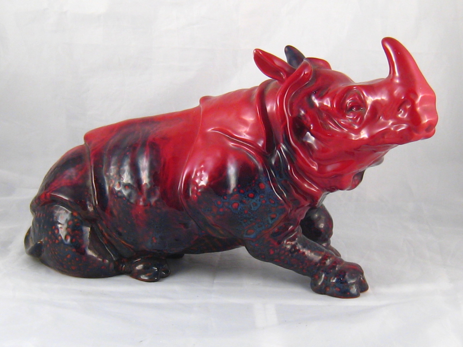 A Doulton ceramic rhinoceros with mottled red flambe glaze,