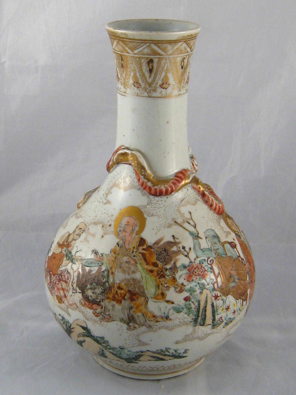 A Meji period Japanese tall necked onion shaped ceramic vase with raised moulded dragon over