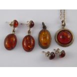 A mixed lot of white metal (tests silver) and amber jewellery comprising two pendants and two pairs