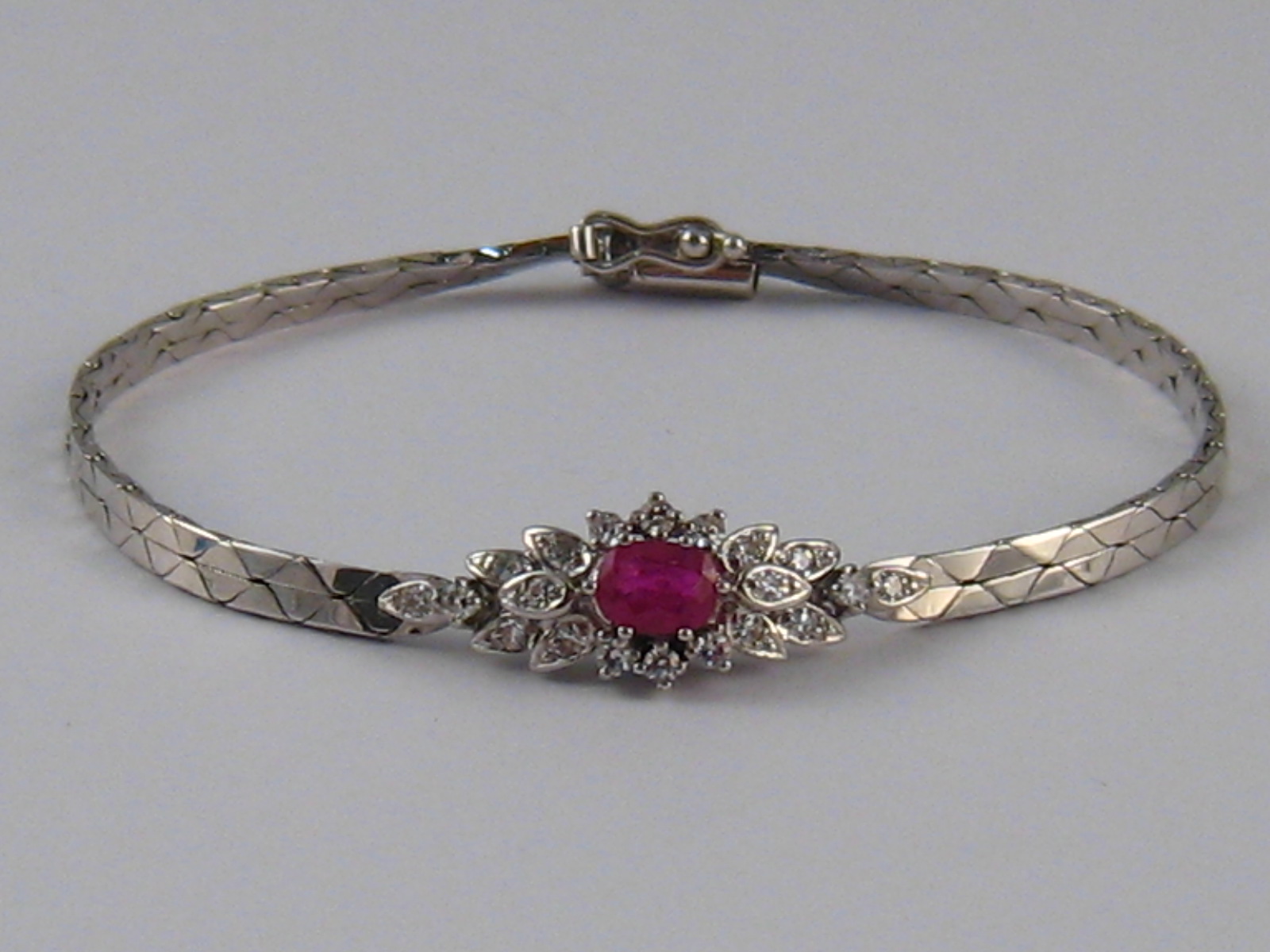 A white metal (tests 14 carat gold) ruby and diamond bracelet, the ruby measuring approx 6 x 4mm,