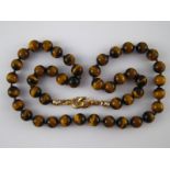 A tiger's eye bead necklace, approx 66cm long, beads approx 11.5mm diameter.