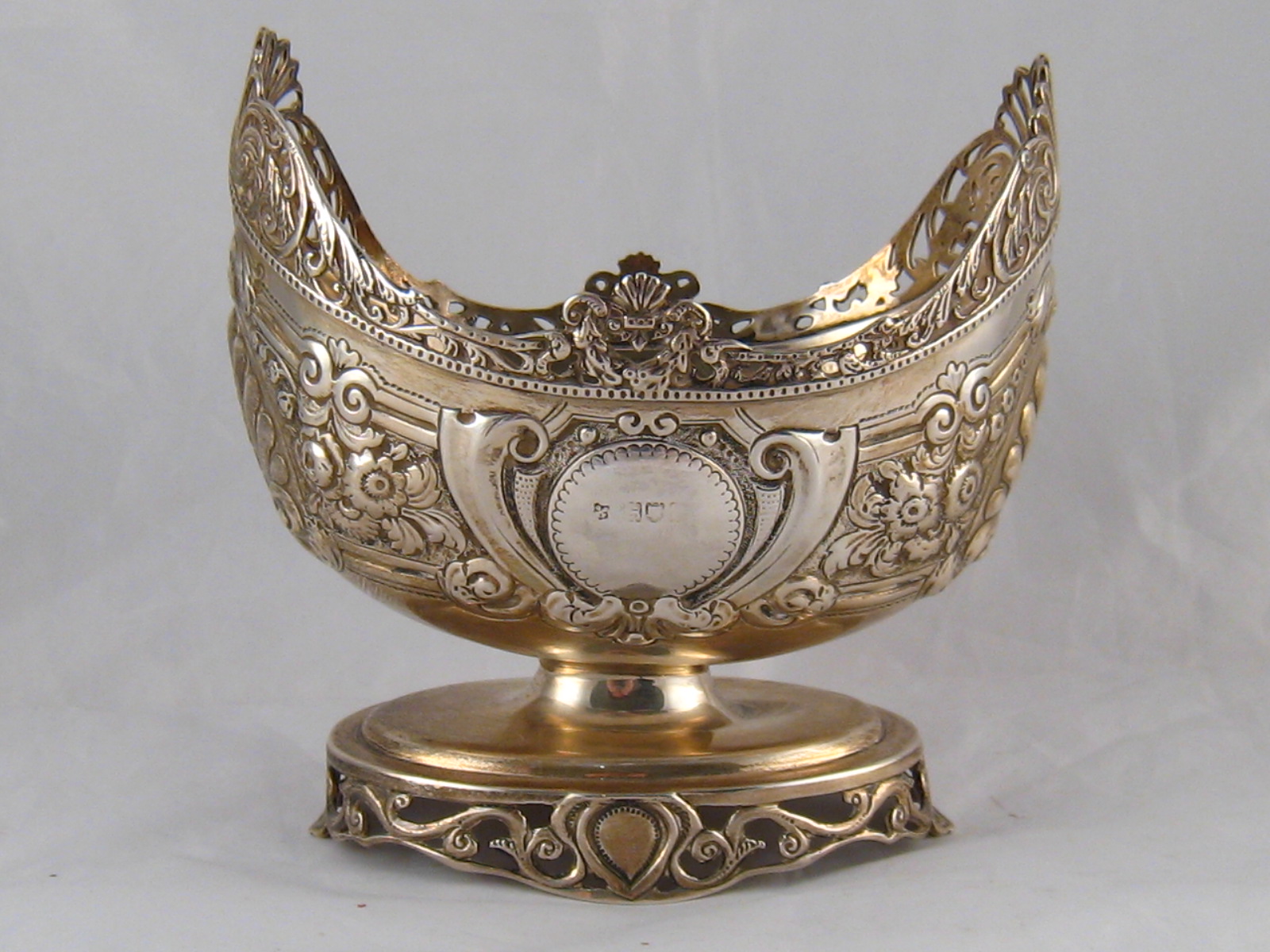 An embossed silver sweetmeats basket with galleried stand foot and pierced scrolling cast rim by