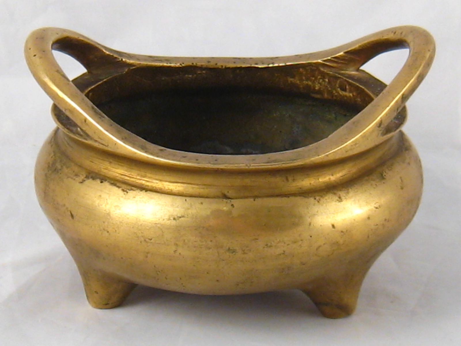 A Chinese bronze censer on three stub feet, inset calligraphy to underside. 11cm. across.