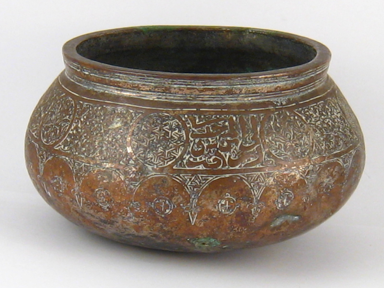 An antique Syrian copper bowl with thickened rim and traces of silvering,