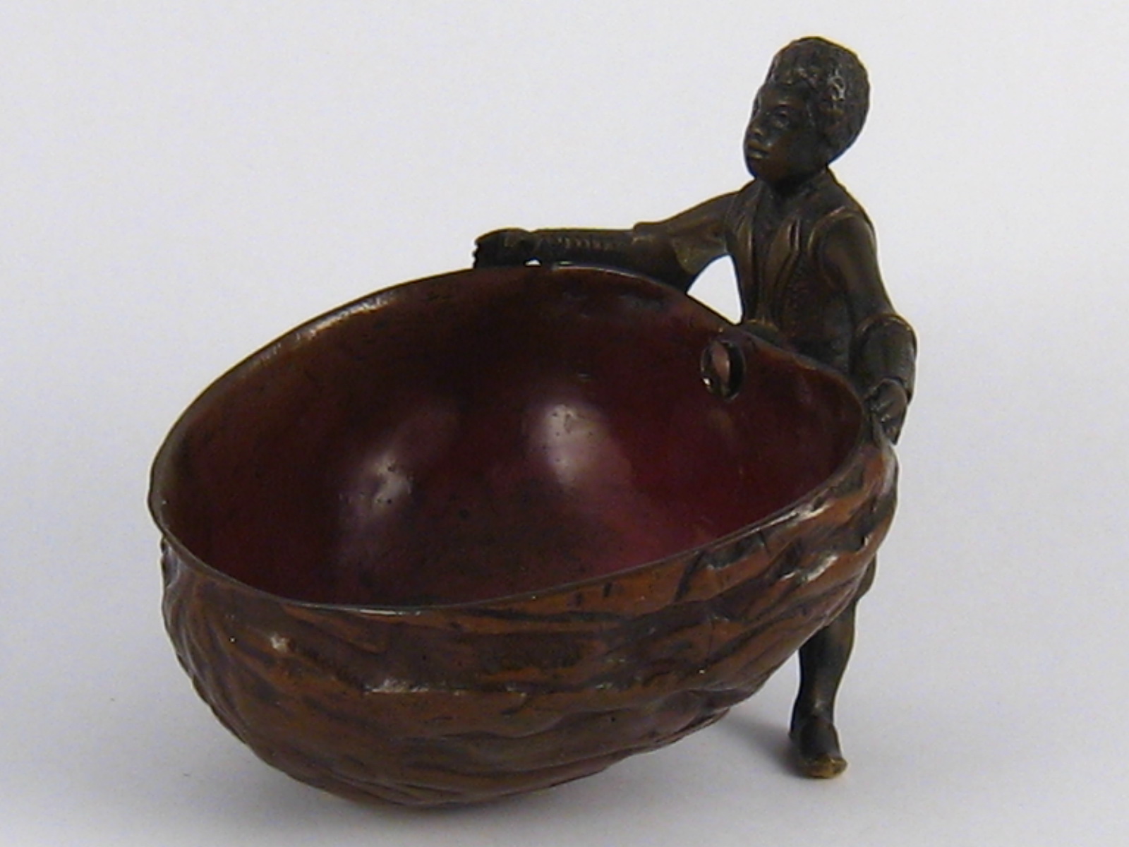 A finely detailed cold painted bronze of an African  boy holding a large walnut shell to form a