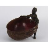 A finely detailed cold painted bronze of an African  boy holding a large walnut shell to form a