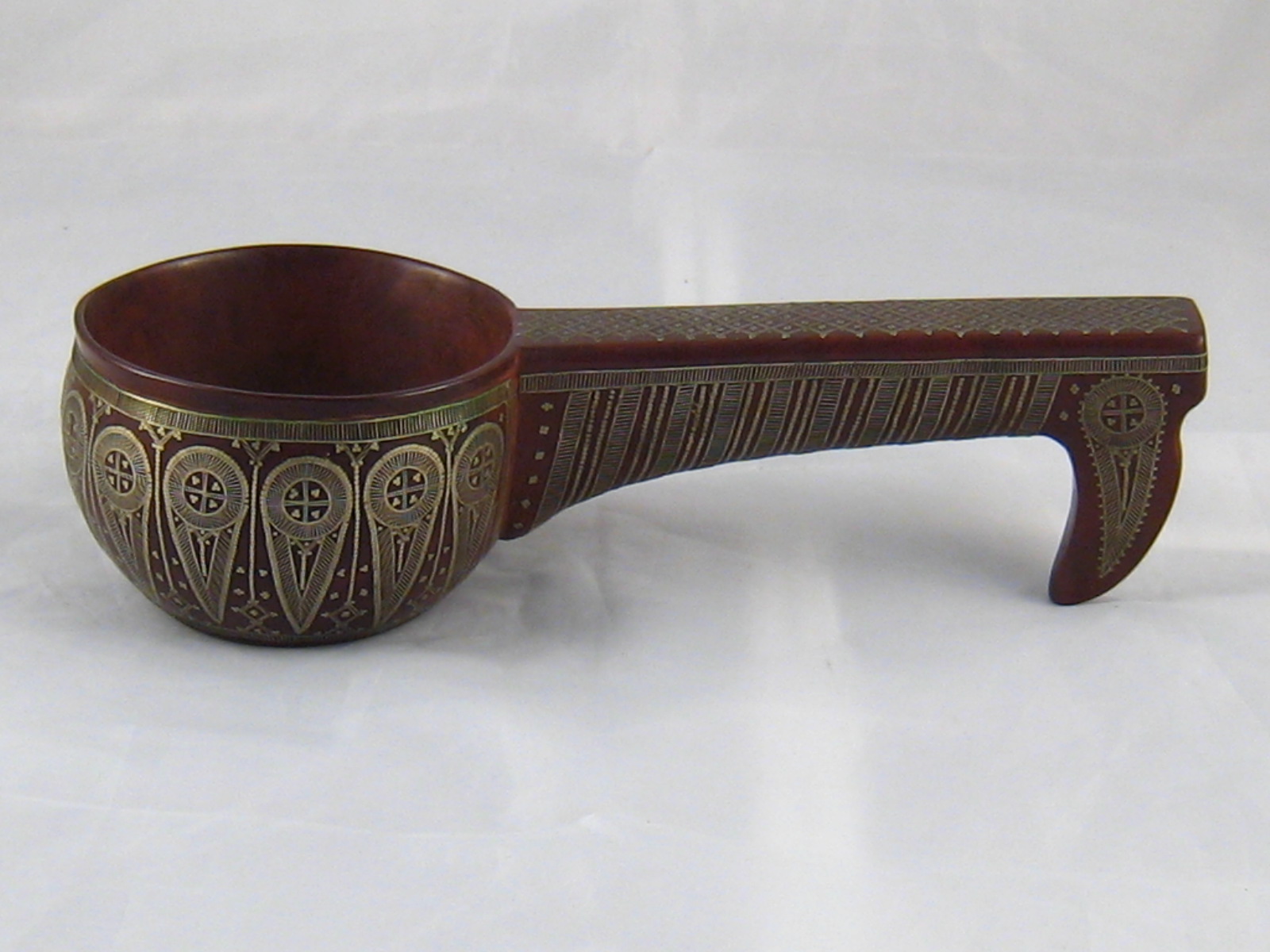 A carved Russian hardwood kovsch with fine inlaid white metal decoration. 22cm. long.