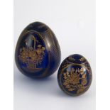 Two dark blue glass Easter eggs, each wheel engraved and gilt with floral images. Hts 9cm. and 6 cm.