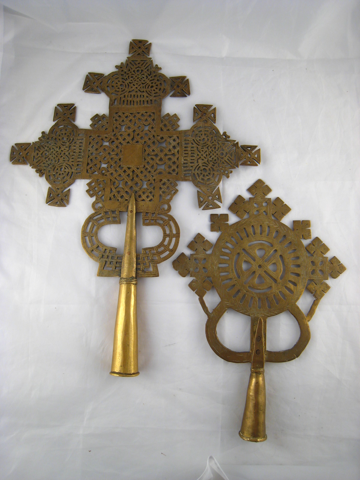 Two Ethiopian brass processional cross finials, one particularly intricately worked. 38x52cm.