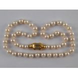 A cultured pearl necklace with a yellow metal (tests 18 carat gold) and diamond clasp,