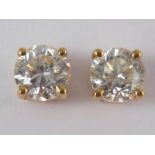 A pair of yellow metal (tests 18 carat gold) round brilliant cut diamond solitaire earrings,