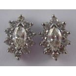 A pair of white metal (tests 18 carat gold) marquise and round brilliant cut diamond ear studs,