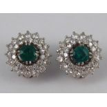 A pair of white metal (tests 18 carat gold) emerald and diamond clip earrings,