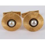 A pair of textured yellow metal (tests 14 carat gold) cultured pearl cufflinks,