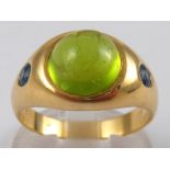 A yellow metal (tests 18 carat gold) cabochon peridot and sapphire ring,