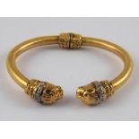 A yellow metal (tests 18 carat gold) bangle (with metal spring),