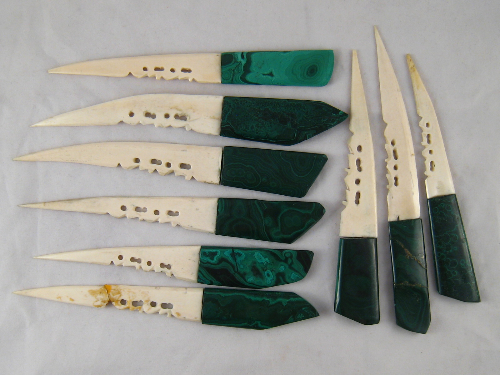 Nine malachite handled letter openers with bone blades, one blade broken.