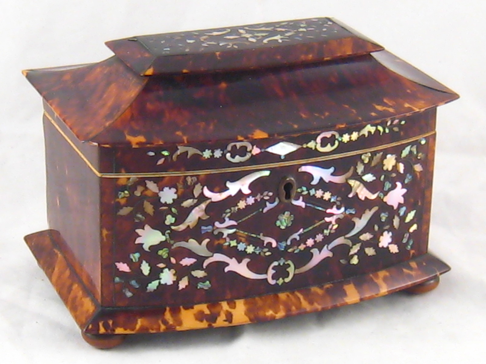 A tortoiseshell bow fronted tea caddy with pagoda lid, lock and key,