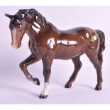 A BESWICK FIGURE OF A STANDING BROWN HORSE with one leg raised. 8.25ins wide.