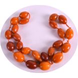 AN EARLY 20TH CENTURY CARVED ORANGE AMBER NECKLACE of good colour and of graduated form. 52 grams.