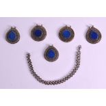 A GROUP OF FIVE INDIAN WHITE METAL MOUNTED LAPIS LAZULI PENDANTS together with a chain. (6)