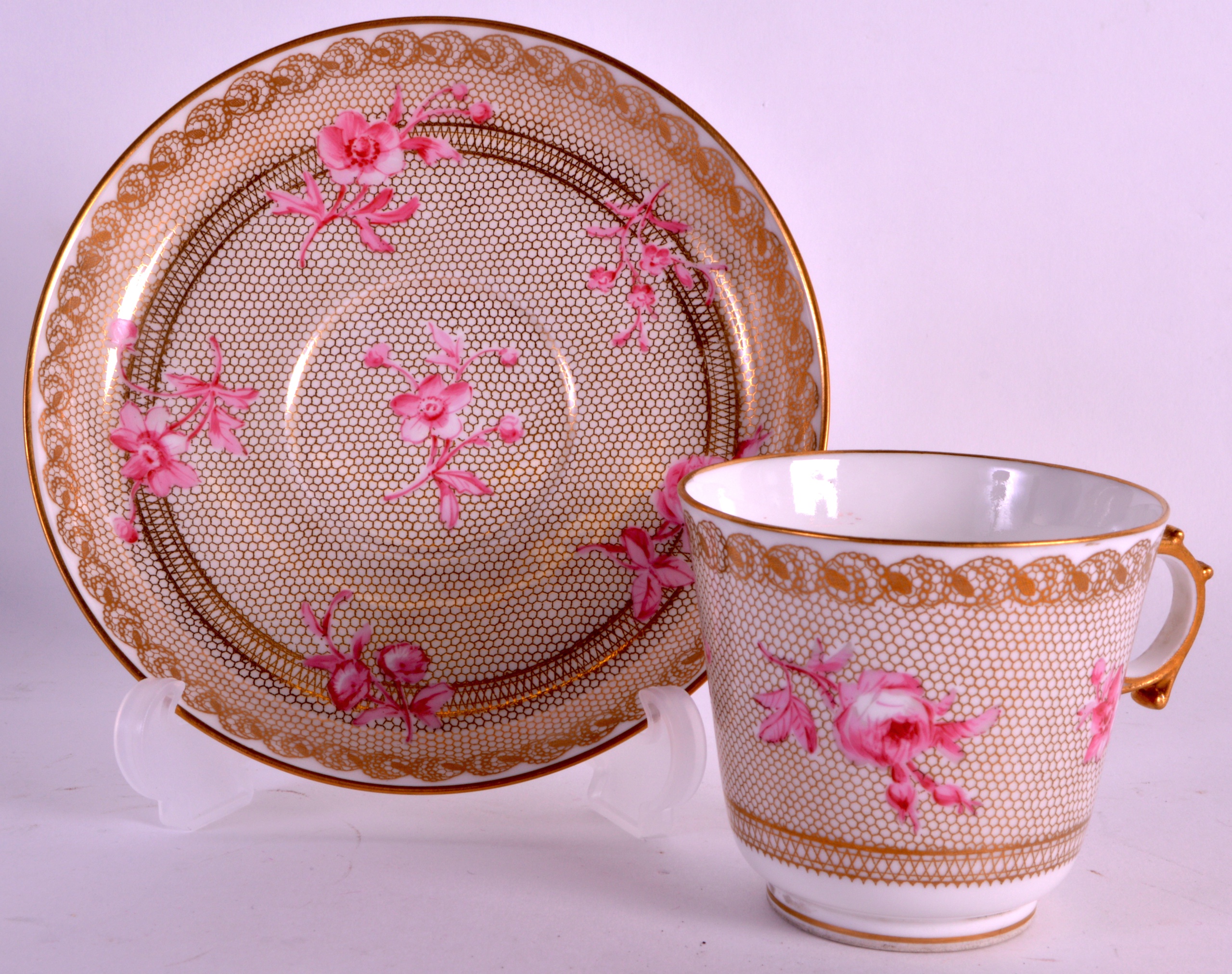 A LATE 19TH CENTURY SEVRES PORCELAIN TEACUP AND SAUCER painted with pink flowers upon a gilt