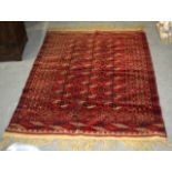 A PERSIAN RED GROUND CARPET decorated with a run of three central motifs within a geometric