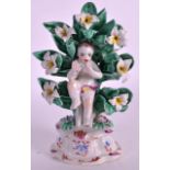 A RARE 18TH CENTURY BOW ARBOUR FIGURE OF A CHILD seated on a chair surrounded by leaves and flowers.