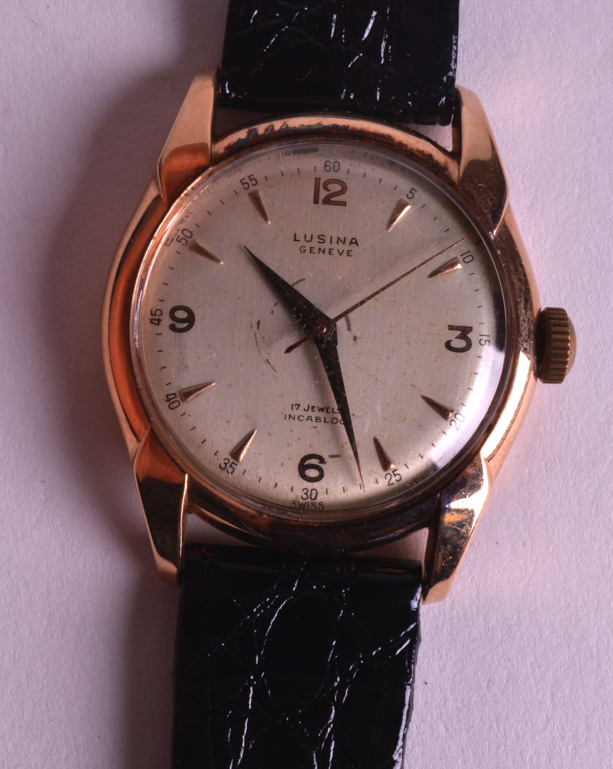 A 1950S 18CT YELLOW GOLD LUSINA GENTLEMANS WRISTWATCH with black leather strap. 1.5ins diameter.