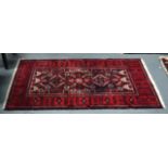 A MID 20TH CENTURY AFGHAN TYPE RUG decorated with motifs upon a deep red ground. 7Ft 2ins x 4ft