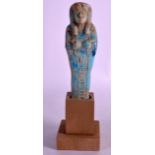 AN EGYPTIAN FAIENCE GLAZED SHABTI supported upon a wooden base. Figure 7.25ins high.