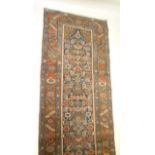 A PERSIAN RUNNER, the indigo field with repeating floral pattern with camel coloured spandrel,