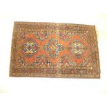 A PERSIAN RUG, the pale red field with three linked guls in indigo and camel and olive green,