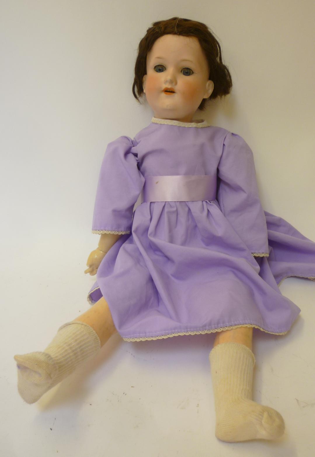 An Armand Marseille bisque head girl doll with blue glass sleeping eyes, open mouth and teeth, brown