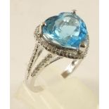 A BLUE TOPAZ AND DIAMOND DRESS RING, the claw set facet cut heart shaped topaz within an open border