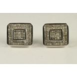 A PAIR OF DIAMOND STUD EARRINGS of canted oblong form pave set with numerous small square cut stones