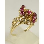 A MODERN RUBY AND DIAMOND COCKTAIL RING, the seven facet cut rubies claw set within scrolls set with