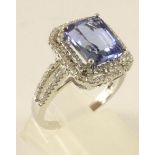 A TANZANITE AND DIAMOND DRESS RING, the claw set emerald cut tanzanite of approximately 4cts