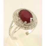 A RUBY AND DIAMOND DRESS RING, the claw set oval cut ruby of approximately 5cts, within a triple