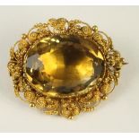 A CITRINE BROOCH, the oval facet cut stone close back set to a filigree border