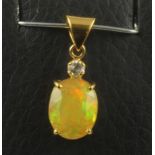 AN AUSTRALIAN OPAL PENDANT, the oval facet cut stone claw set in yellow gold below a small diamond