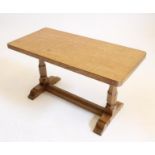AN ADZED OAK COFFEE TABLE by Wilf Hutchinson "Squirrel Man", of rounded oblong trestle form, the