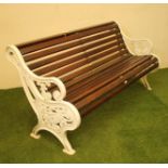 A CAST IRON PARK BENCH of scroll back form with slatted wood seat and back, scrolled arms, the