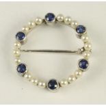 A SEED PEARL AND SAPPHIRE CIRCLET BROOCH, the eighteen pearls interspersed with six open back collet