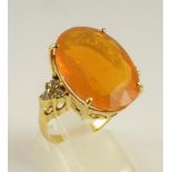 A FIRE OPAL DRESS RING, the oval facet cut stone of approximately 15cts claw set to shoulders each